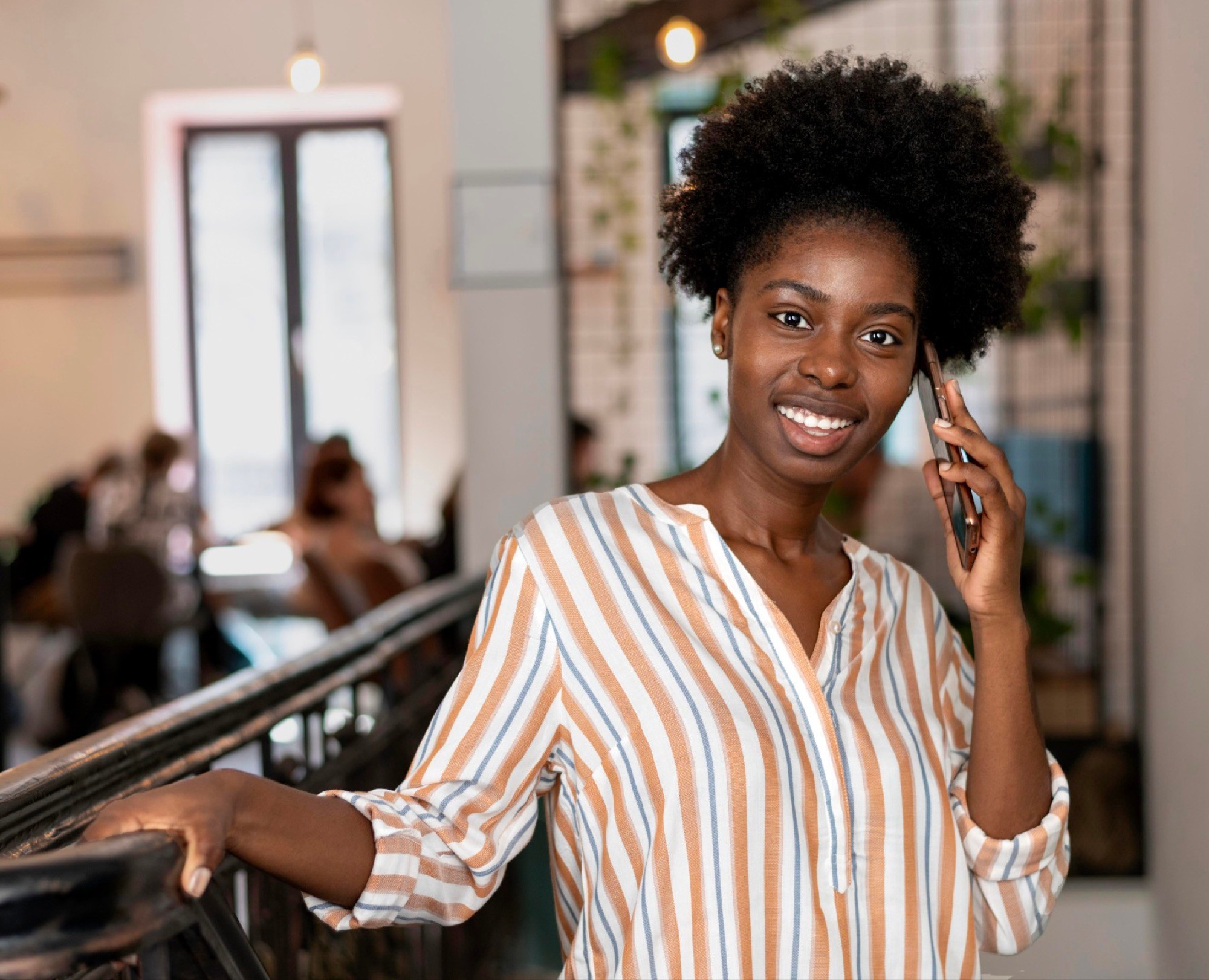 Woman smiling on a phone call in a café